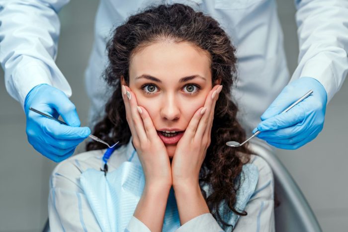 woman expressing fear with dentist holding dental tools need to see dentist Marietta Georgia